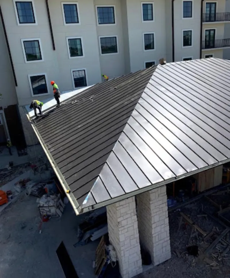 Crew installing standing seam metal roof panels on a commercial project in Eureka